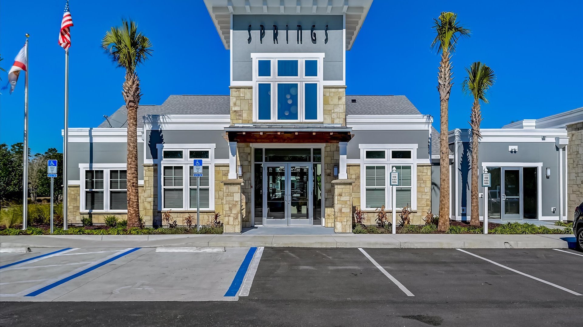 Clubhouse Entrance with Palm Trees and ample Parking at Springs at Flagler Center Apartments in Jacksonville, FL