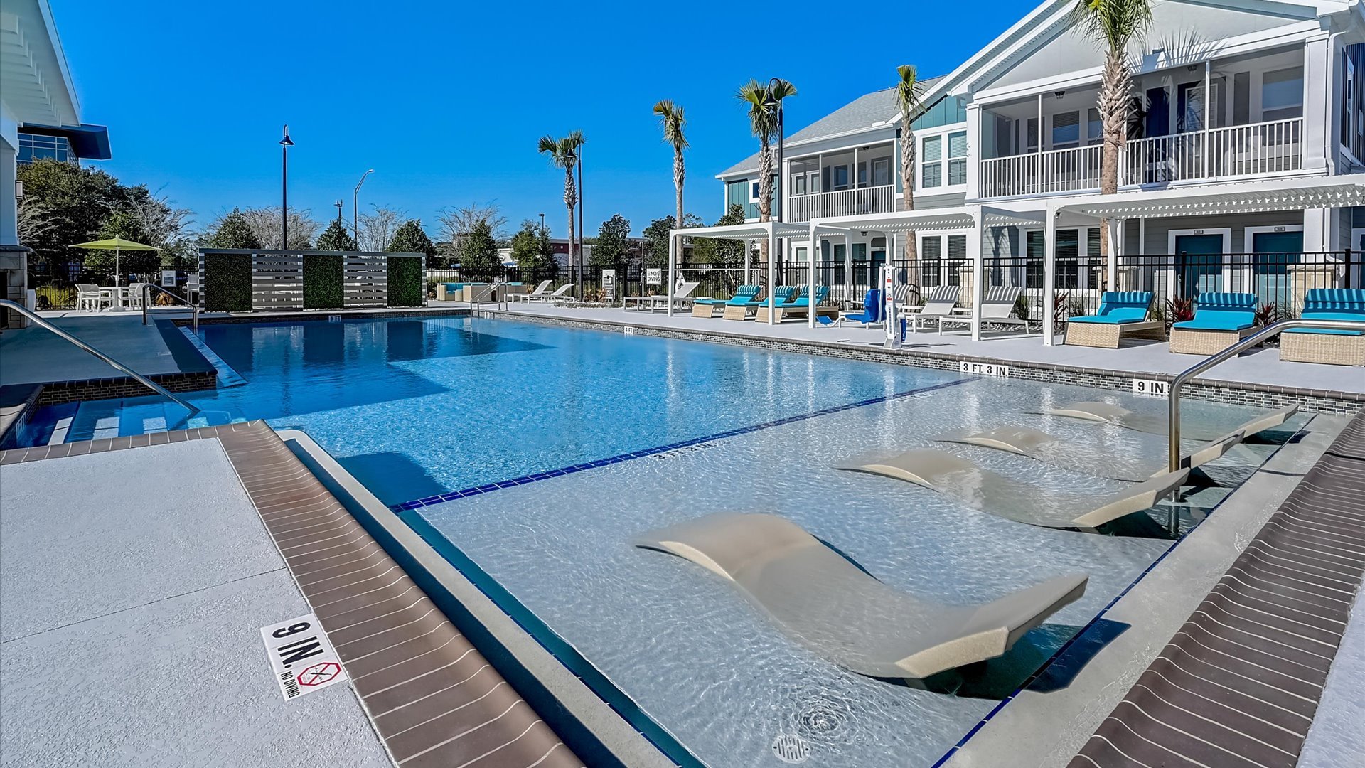 Pool Amenity with Lounge Chairs and Stunning Townhomes in the background. 