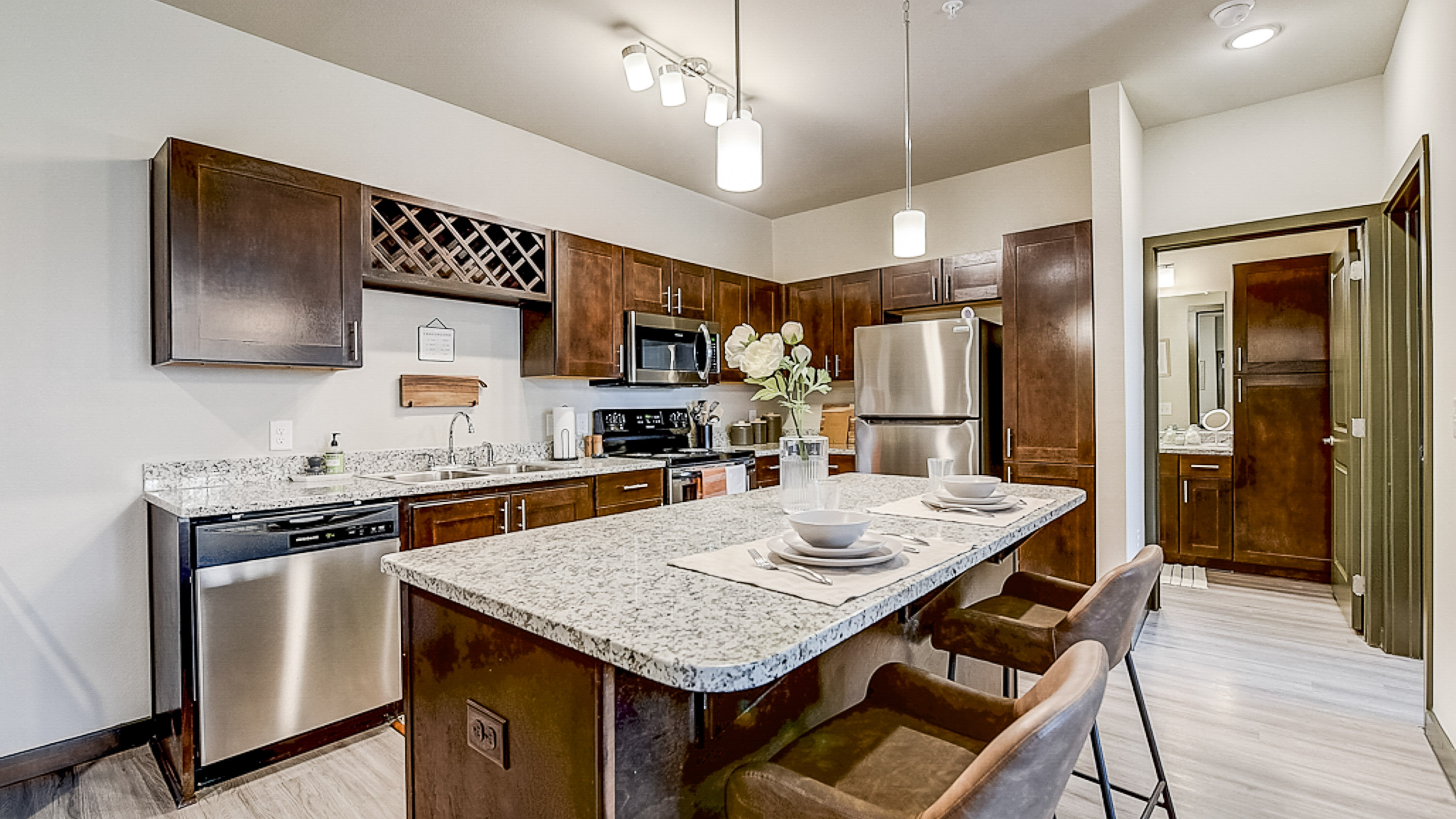 Stainless Steal appliances, granite counter tops, wine rack, and brown wood cabinets at Springs at Grand Prairie apartments in Texas