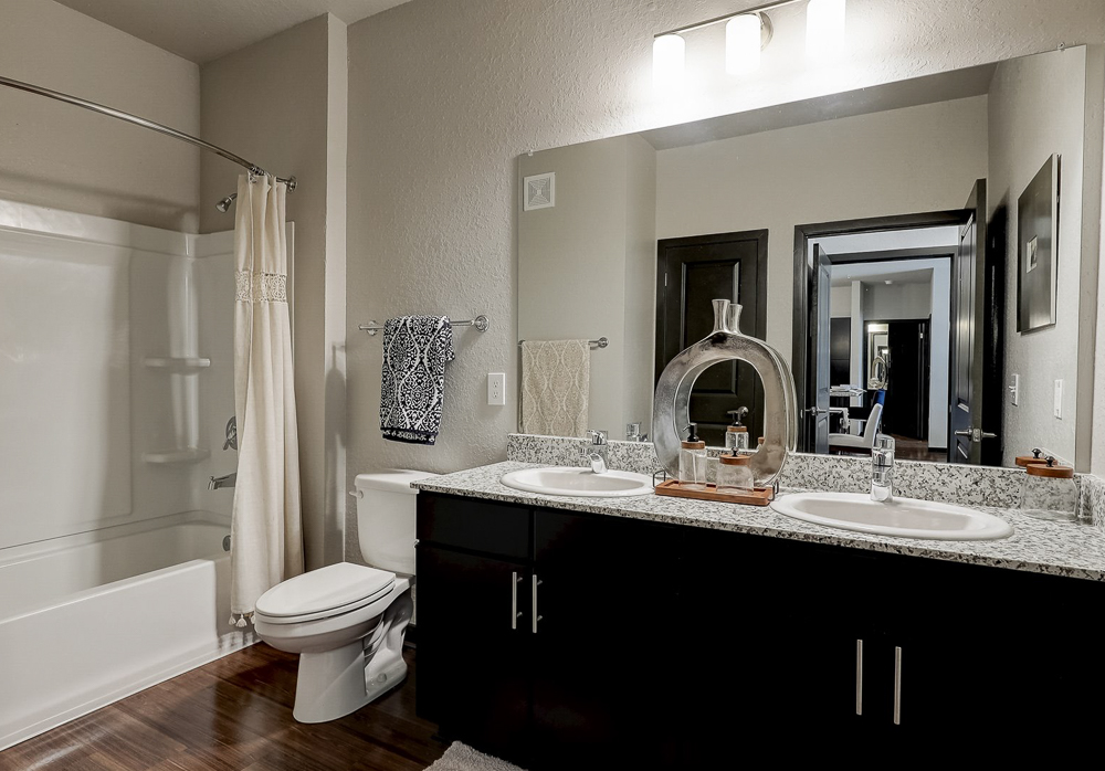 Bathroom with garden tub, granit counters, and large mirror over a double sink with espresso cabinets at Springs at Newnan Apartments in Georgia-61
