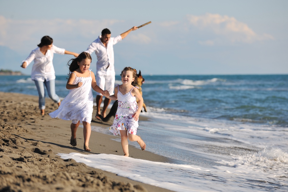 happy young family in white clothing have fun and play with beautiful dog at vacations on beautiful beach.jpeg